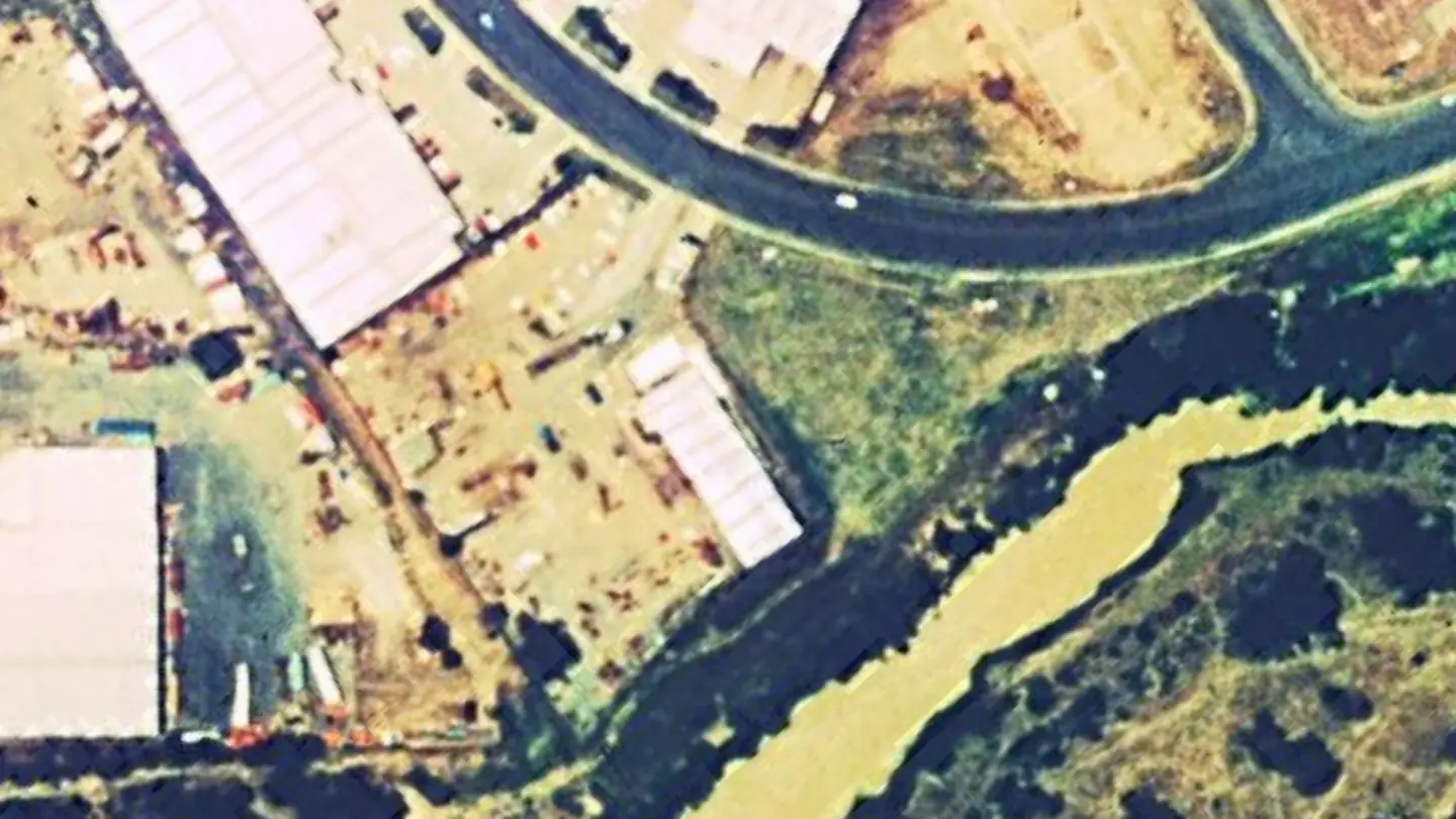 Aerial view of 53 Success Street in 1994: a single shed near the creek on an otherwise open block