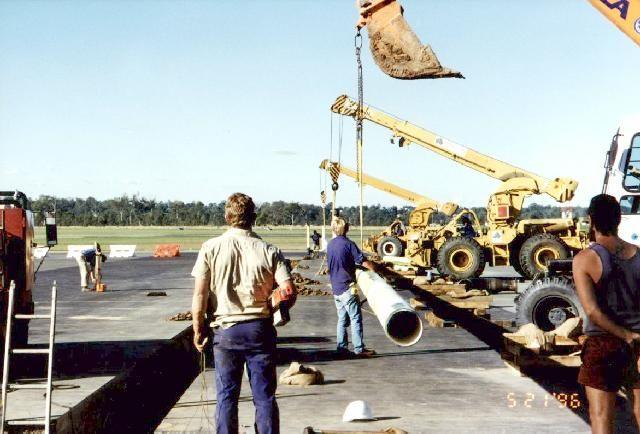 Crews managing a crane lift of large pipe sections at Amberley