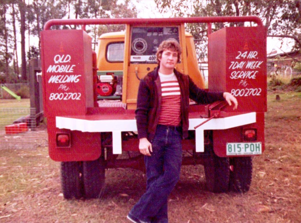 Jeff Samuels standing at the back of the red Queensland Mobile Welding service ute in 1984, its toolboxes signwritten “24 hr 7 day week service”