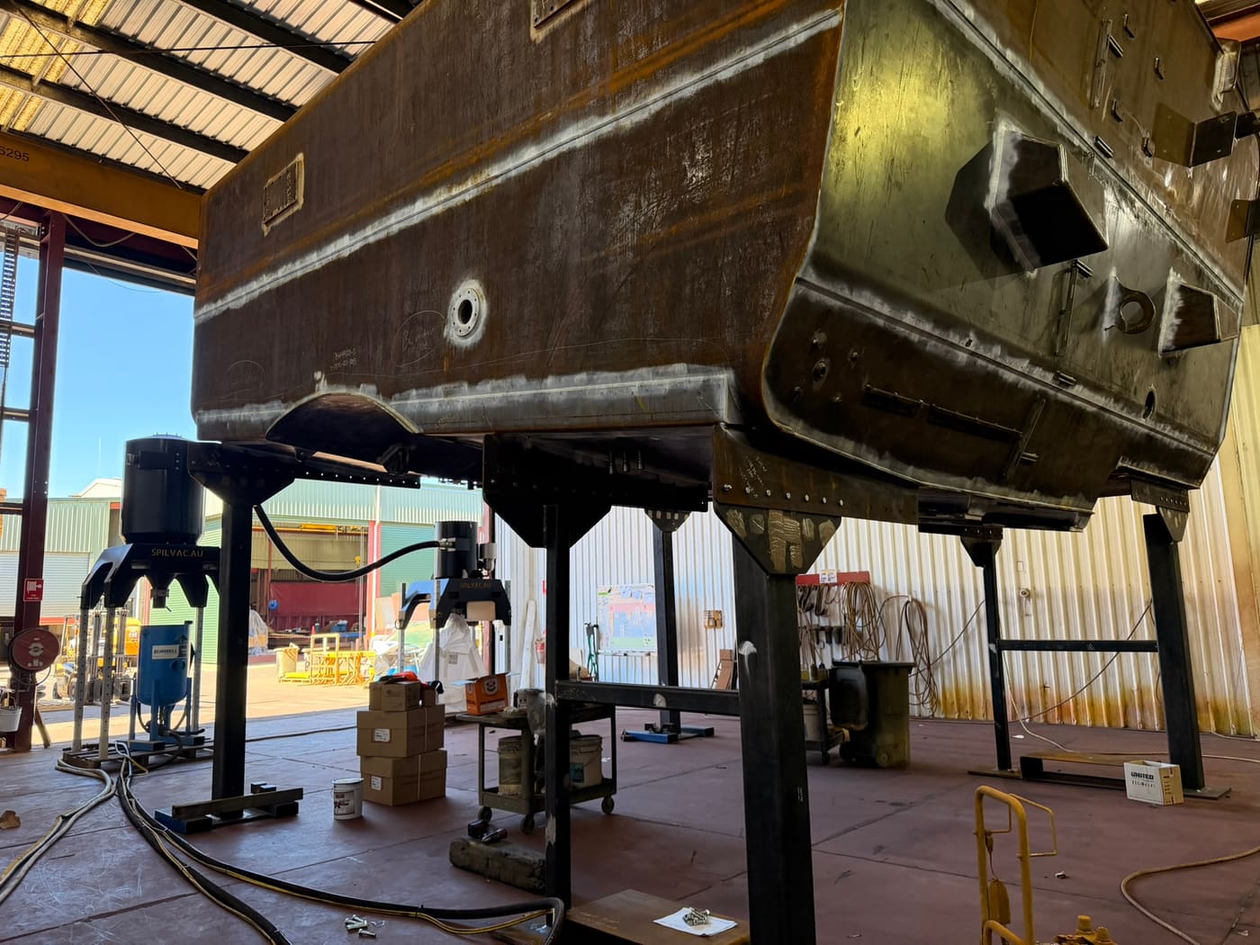 Underside of a blasted haul truck body supported on stands