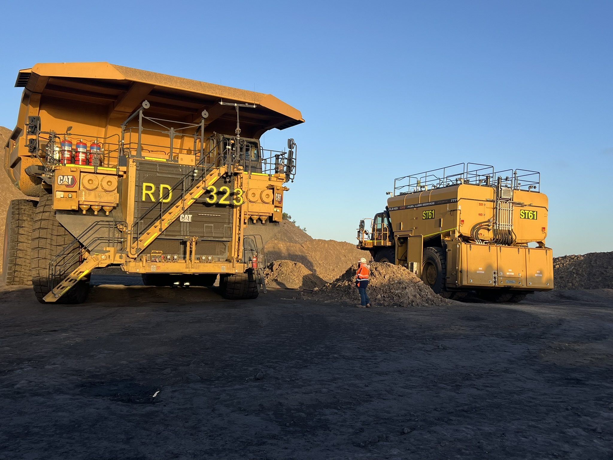 A QMW FLS-63 fuel and lube service truck working alongside a CAT haul truck at a coal mine at first light